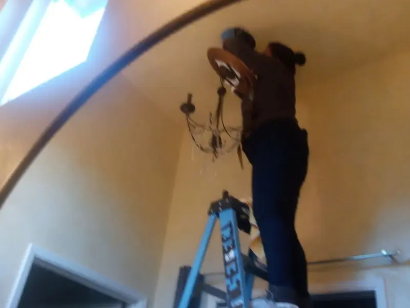 Electrician installing a chandelier in a East End residence